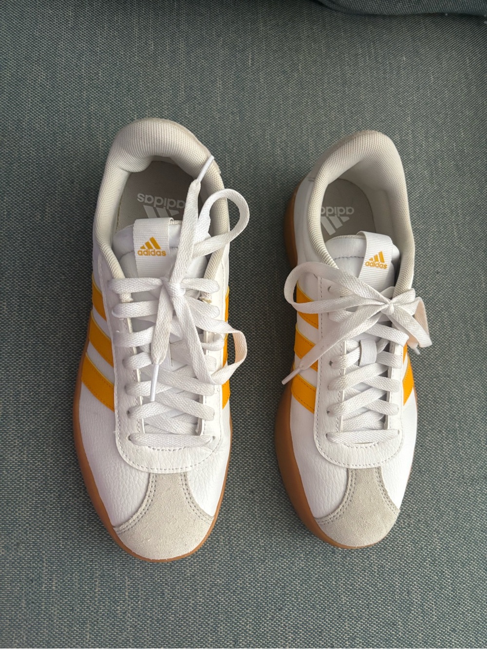 Adidas VL Court 3.0 sneakers featuring a white upper with orange stripes.